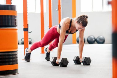 Geniş hafif spor salonundaki işlevsel eğitim sırasında atkuyruğu olan, halterli güçlü bir sporcu.