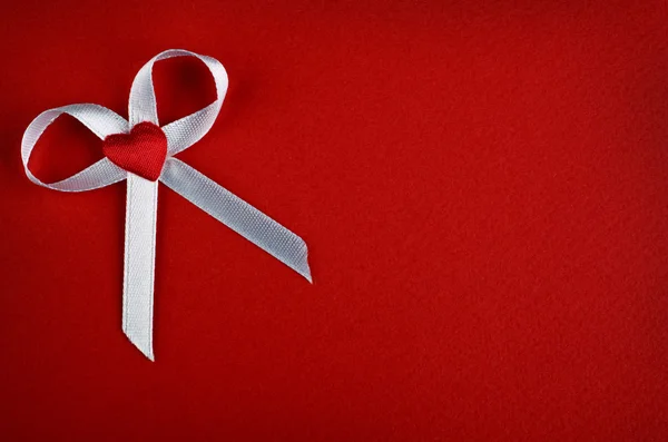 White bow with heart on a red background — Stock Photo, Image