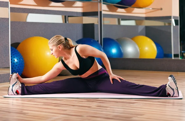 Blonde performs exercises in sports hall — Stock Photo, Image