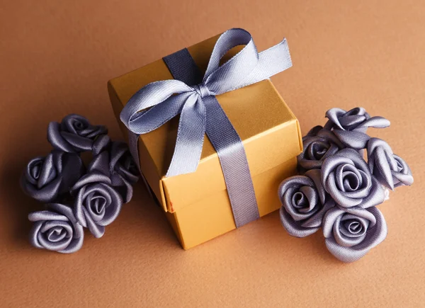 Artificial flowers and golden gift box — Stock Photo, Image