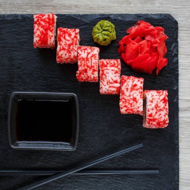 Deniz ürünleri ve soya soslu suşi, wasabi ve zencefil. Siyah tahtada havyarlı suşi rulosu..