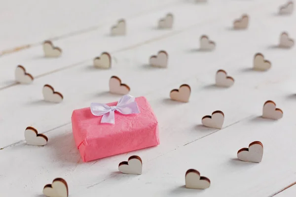 Маленький Подарок Завернутый Розовую Бумагу Декоративные Сердца Вокруг Подарка Белом — стоковое фото