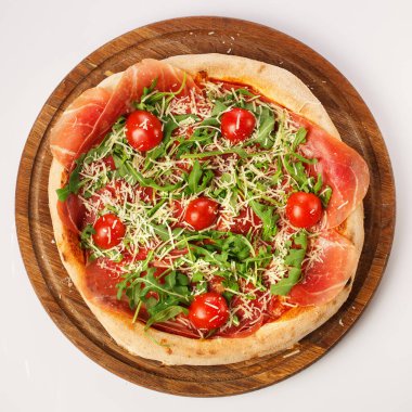 Tahta tezgahta sıcak pizzanın en üst görüntüsü. Prosciutto, domates, Hollanda peyniri.