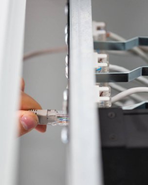 Establishing connection. Close up of technician connecting network cable to check server. Male hand installs internet cable in fuse box. Network connection concept