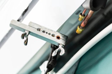 Close up of specialized tool for connecting copper pipes when installing air conditioning. Metal clamp with various holes for connecting pipes to air conditioning system.