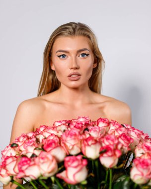 Sensual young woman with bare shoulders holding bouquet standing on white background. Sensual young woman with bare shoulders holding bouquet standing on white background. Feminine concept.