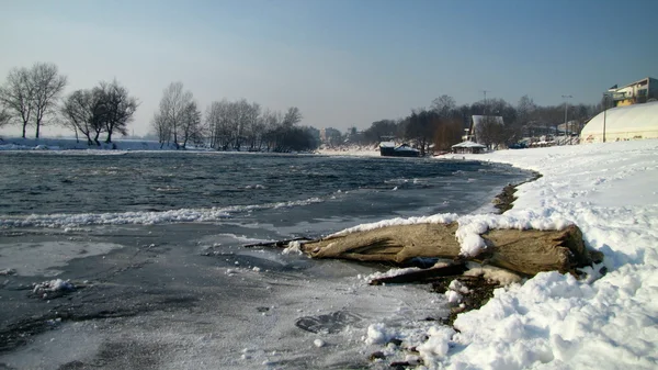 Winter landscape of frozen river with a log on riverside — Stock Photo, Image