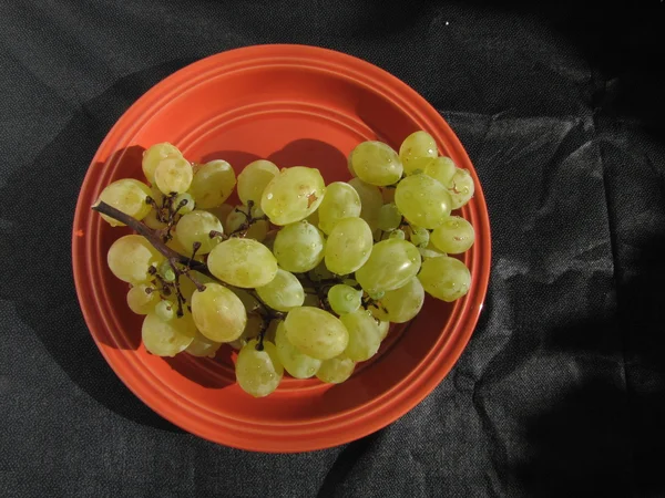 Uvas blancas en un plato naranja sobre fondo de lona negra —  Fotos de Stock