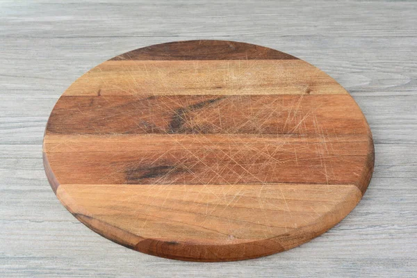 Gri ahşap zemin üzerinde boş yuvarlak ahşap doğrama tahtası, üst görünüm, kopyalama alanı