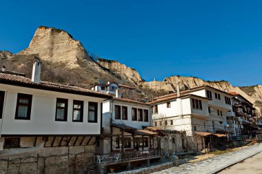 Melnik, Bulgaristan - 18 Mart 2012: Bulgaristan 'ın Melnik kentindeki ünlü kum piramitlerinin arka planına karşı eski geleneksel evler. Ziyaret yerinde.. 