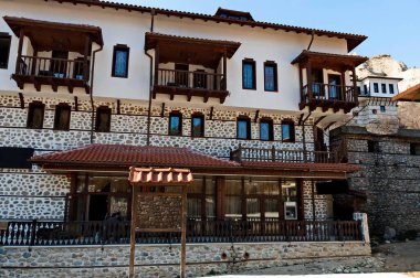 Melnik, Bulgaristan - 18 Mart 2012: Bulgaristan 'ın Melnik kentindeki ünlü kum piramitlerinin arka planına karşı eski geleneksel evler. Ziyaret yerinde..