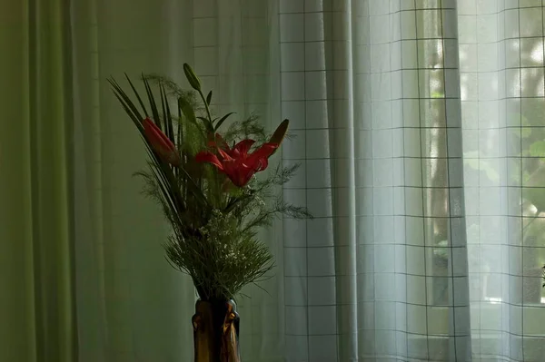 Strauß Aus Roten Lilien Palmblättern Und Zartem Gras Einer Glasvase — Stockfoto