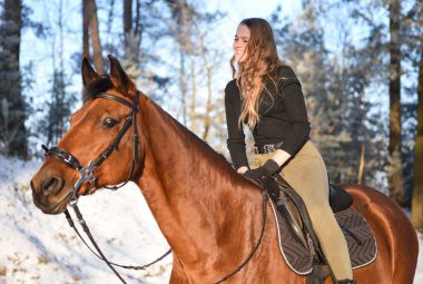 Young girl with horse on winter forest road.