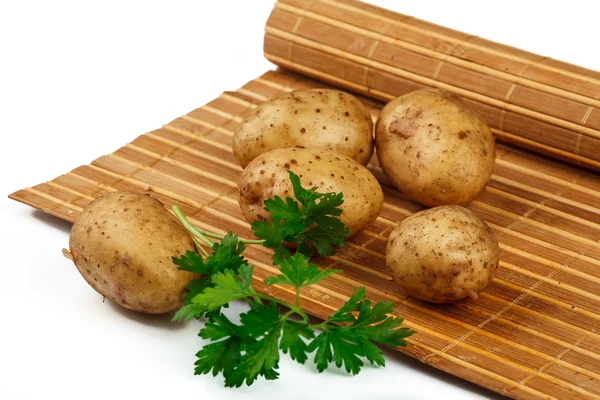 Aardappelknollen met een takje peterselie op de mat — Stockfoto