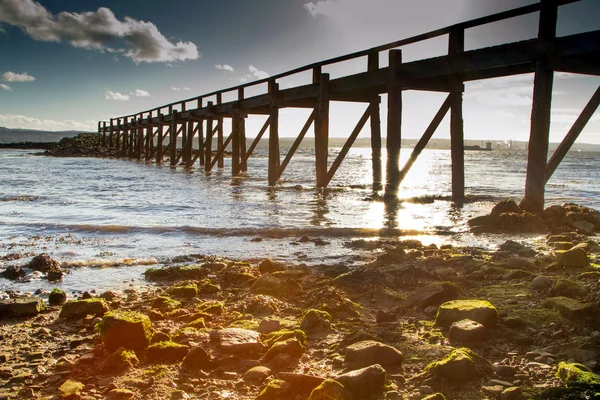 Solen strålar spricker igenom pier — Stockfoto