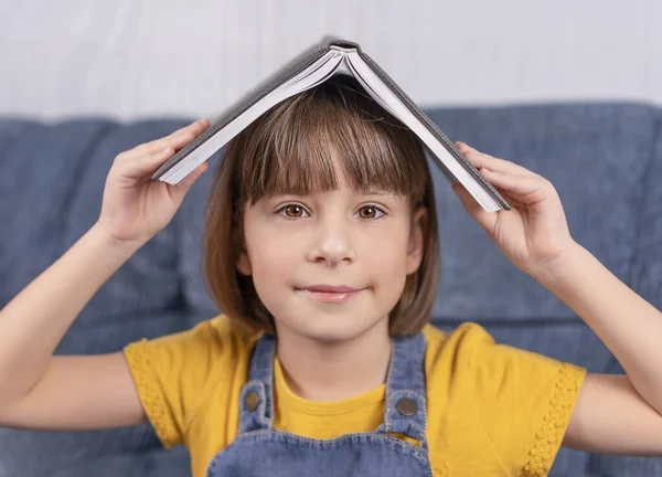 Маленька Дівчинка Тримає Книжку Під Головою Посміхається — стокове фото
