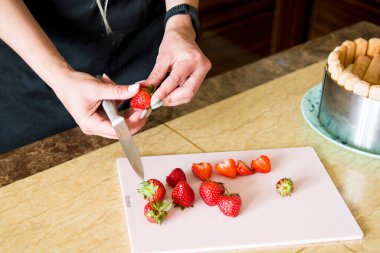 Birisi mutfakta çilek kesiyor.