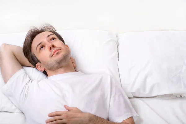 Denkender junger Mann liegt auf dem Bett — Stockfoto