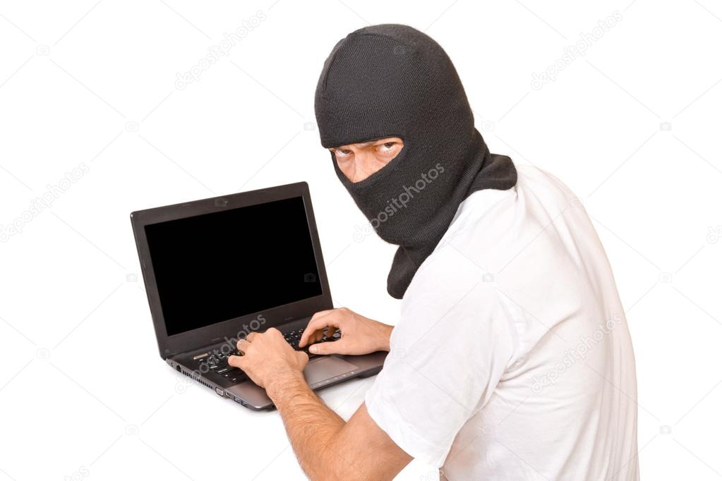 Man in black mask looking at camera and typing something
