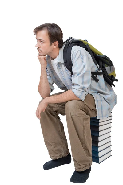 Junge mit Rucksack sitzt auf Bücherstapel — Stockfoto
