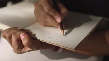 Kadın eli kalemle bir not defterine yazıyor.