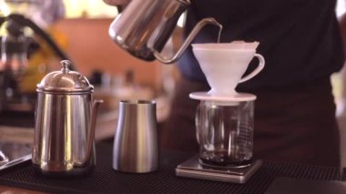Kahve yapan baristanın yavaş çekimde çekilmiş görüntüsü. Süzgeç damlayan su işlemiyle sıcak kahve yapıyor. Sabah evde ya da kafede ev yapımı kahve yapıyor.