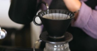 Kahve yapan baristanın yavaş çekimde çekilmiş görüntüsü. Süzgeç damlayan su işlemiyle sıcak kahve yapıyor. Sabah evde ya da kafede ev yapımı kahve yapıyor.