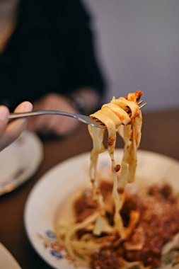 woman hand holding fork with large portion of pasta