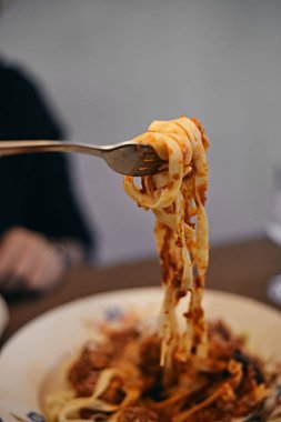 woman hand holding fork with large portion of pasta