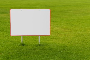 Yeşil çimlerin üzerindeki boş reklam panosu