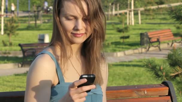 Sonriente joven mensajería de texto en el teléfono — Vídeos de Stock