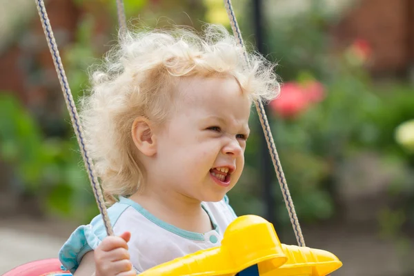 Adorável loira cabelo encaracolado menina se divertindo em um balanço — Fotografia de Stock