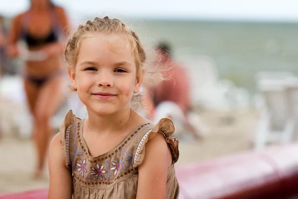 Beautiful girl sitting and smiling on a beach — Stock Photo, Image