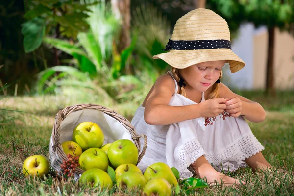 Девушка сидит на траве с корзиной яблок — стоковое фото