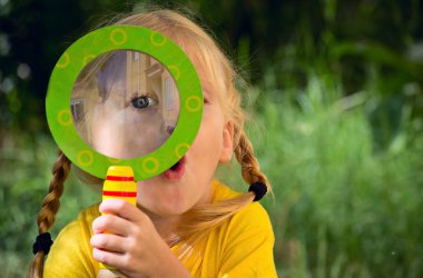Girl with surprise looks through a magnifying glass clipart