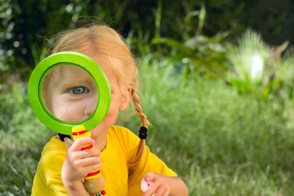 Fille avec surprise regarde à travers une loupe — Photo