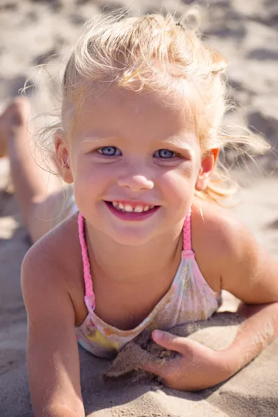 Meisje liggend op het zand van de zee — Stockfoto