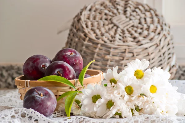 Still life with plums and flowers — Stock Photo, Image