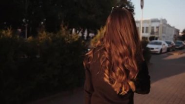 Kafasında güneş gözlüğü olan zarif bir genç kız şehirde dolaşıp lüks saçlarını düzeltiyor. Moda ve tarz kavramı