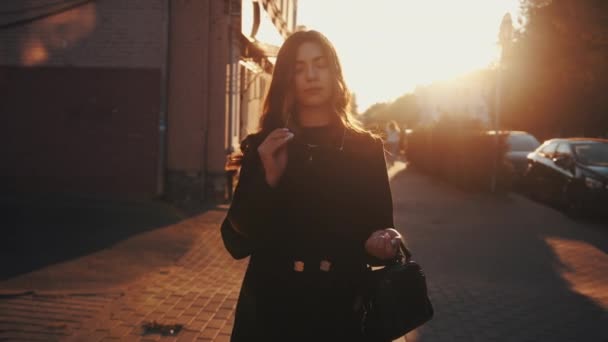 Vynikající mladá dáma si nasadí sluneční brýle a narovnává své luxusní vlasy, zatímco stojí na ulici při západu slunce — Stock video