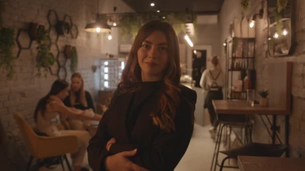 En spektakulär ung flicka i svarta kläder står i lobbyn i ett elegant café och uträtning hennes långa hår. Långsamma rörelser — Stockvideo