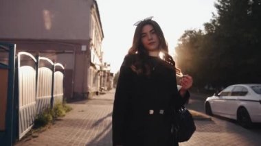 Şık siyah elbiseli güzel bir genç kız gün batımında şehirde dolaşır ve kafasına güneş gözlüğü takar. Yavaş çekim