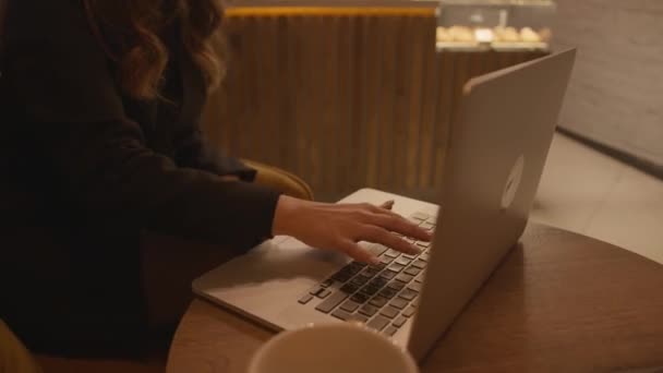 Une jeune fille est assise à une table dans un café et travaille sur un ordinateur portable. Les mains en gros plan. Travail à distance et concept freelance — Video