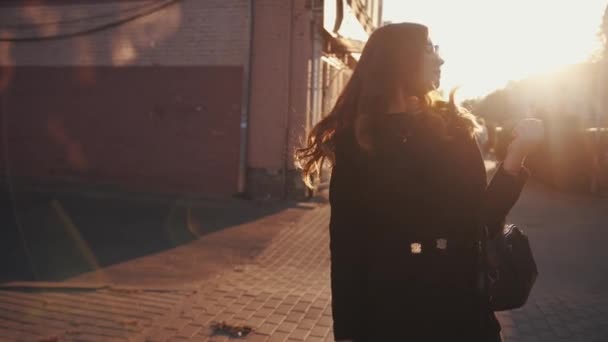 Portret van een spectaculair jong meisje in een zonnebril gaat langs de straat van de stad en draait naar de camera rechttrekken haar prachtige haar. Langzame beweging — Stockvideo
