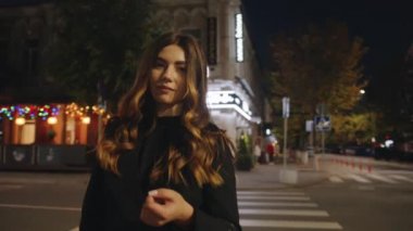 Şık bir genç kız gecenin ilerleyen saatlerinde neon ışıklarının ve renkli bir çelengin önünde bir kavşakta duruyor. Yavaş çekim