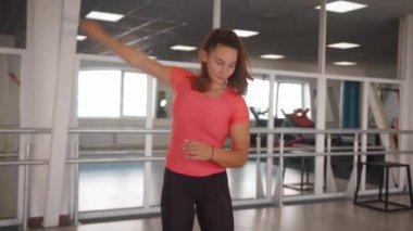 Pembe tişörtlü güzel kız antrenmandan önce ısınıyor ve elleriyle dairesel hareketler yapıyor.