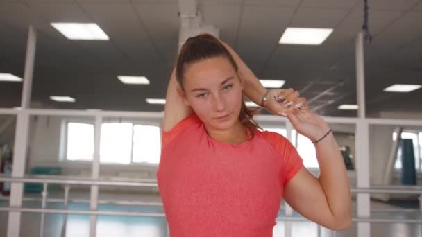 Spor salonundaki dayanıklılık eğitimini tamamlayan ve triseps esneme hareketleri yapan güzel bir genç kız. Spor ve sağlıklı yaşam tarzı kavramı — Stok video