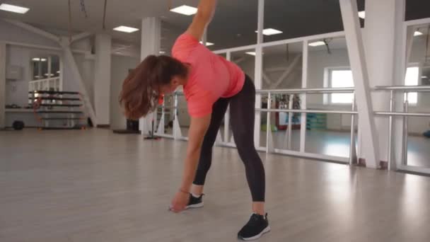 Młoda dziewczyna dochodzi do siebie po treningu siłowym i wykonuje ćwiczenia młyna, aby ćwiczyć mięśnie jamy brzusznej i poprawić postawę pleców — Wideo stockowe