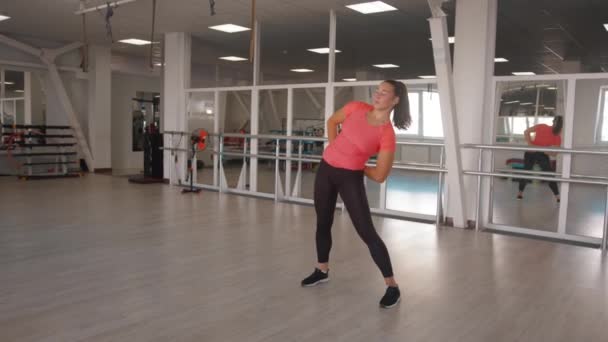 A young girl stretches after strength training in the gym and does body rotations and forward bends to stretch her back and legs — Stock Video