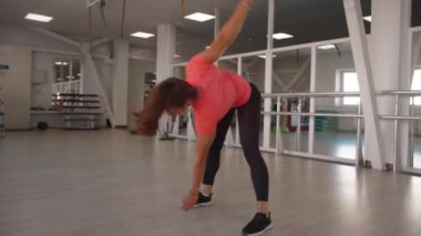 Spor salonundaki genç kadın, bel bölgesini daraltmak ve genel tonu arttırmak için kasları tonu değiştiriyor.